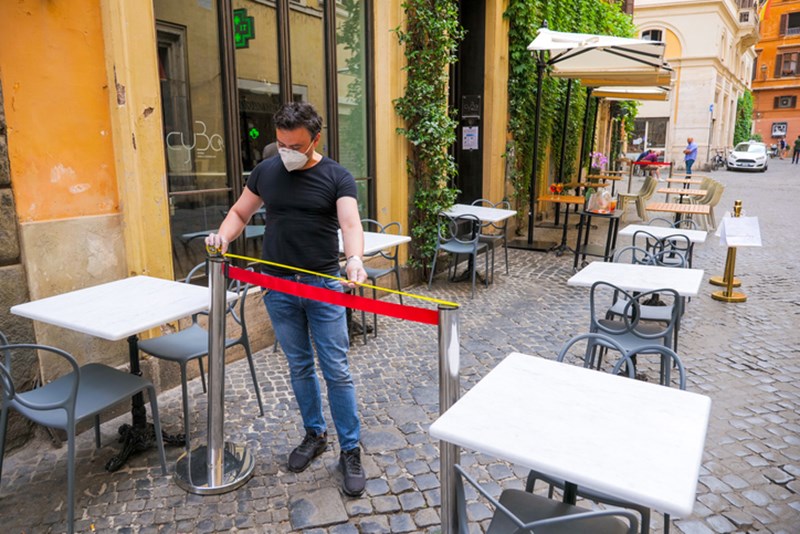 A WAITER MEASURES THE SPACE BETWEEN TABLES