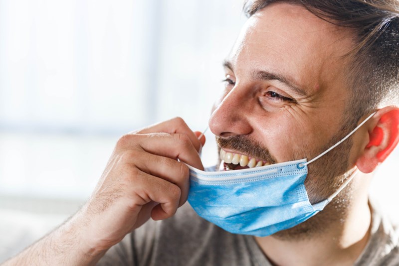 MAN TAKING OFF HIS PROTECTIVE MASK