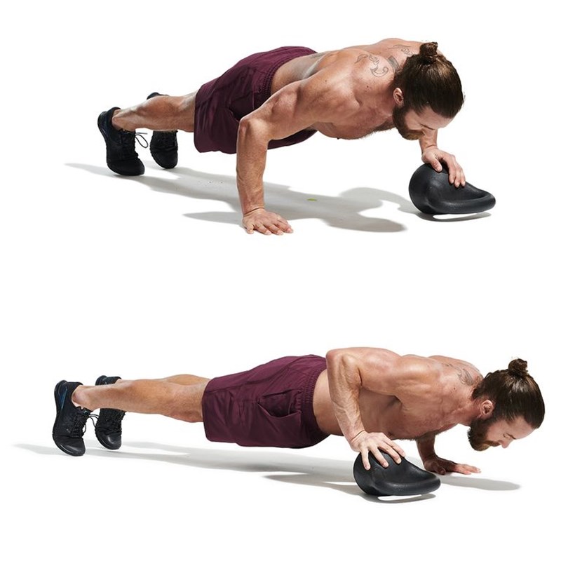 MAN PERFORMING PRESS-UP OVER KETTLEBELL