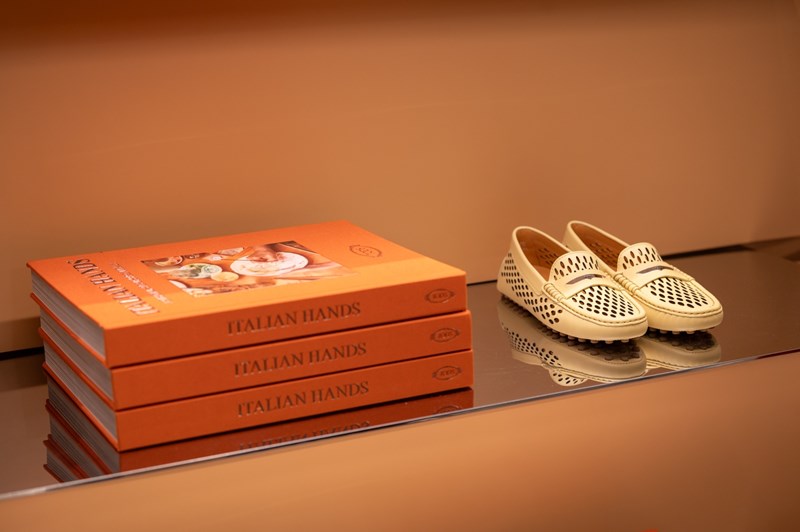 Το βιβλίο Ιστορίες Χειροτεχνίας από την Ιταλία δίπλα σε ένα ζευγάρι Tod's