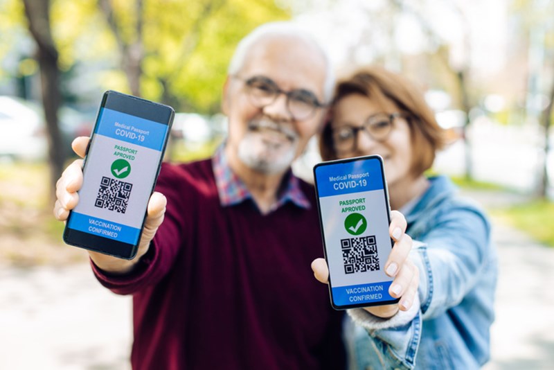 COUPLE SHOWING SMARTPHONES WITH ELECTRONIC VACCINATION CERTIFICATES