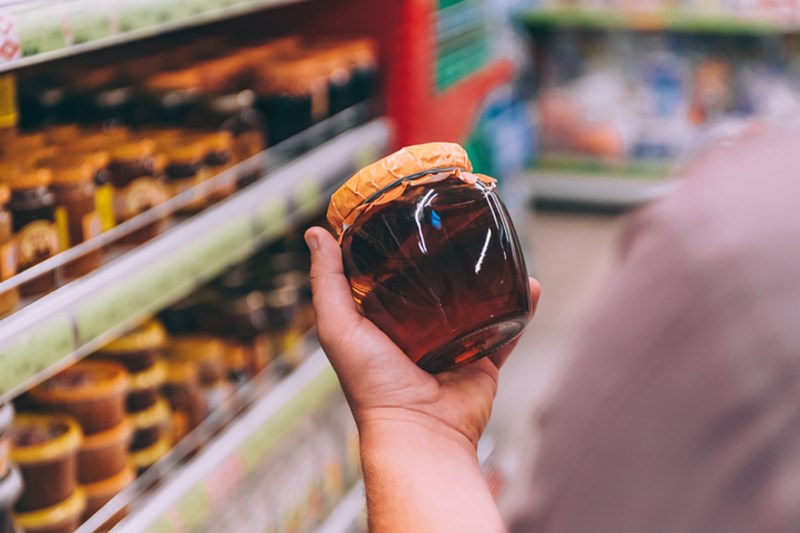 MAN HOLDING A JAR WITH HONEY