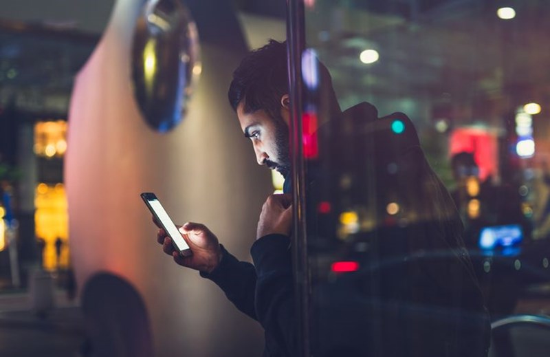 MAN LOOKING AT HIS CELL PHONE